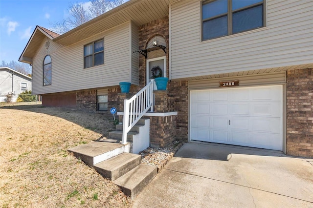 bi-level home with concrete driveway, an attached garage, and brick siding