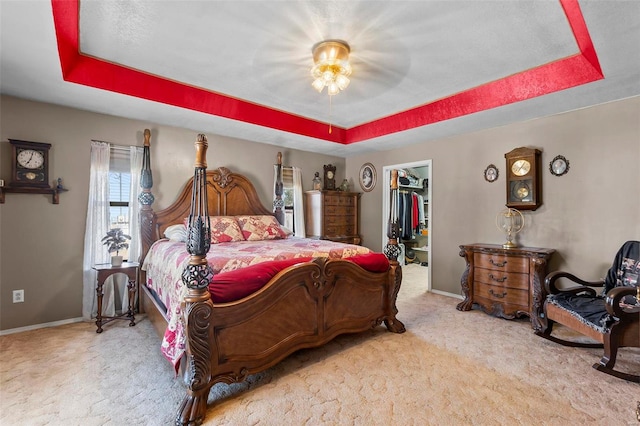 bedroom with a spacious closet, carpet flooring, and a raised ceiling