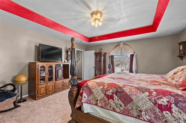 carpeted bedroom featuring baseboards, a raised ceiling, and a textured ceiling