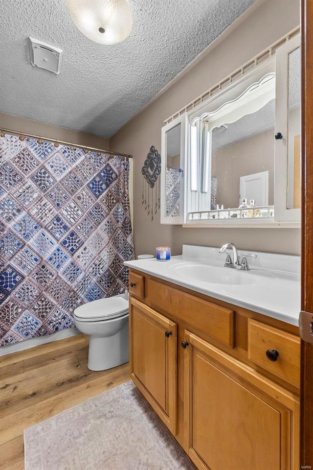 bathroom with toilet, wood finished floors, vanity, and a textured ceiling