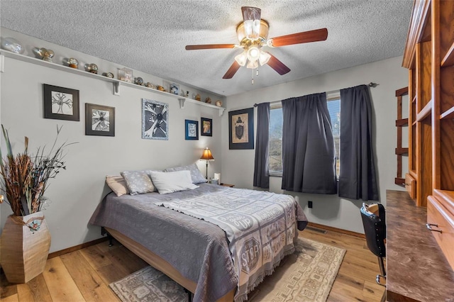 bedroom with light wood-type flooring, baseboards, and a textured ceiling