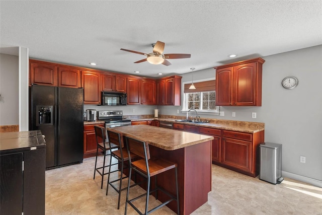 kitchen with black appliances, a ceiling fan, a sink, a kitchen island, and a breakfast bar area