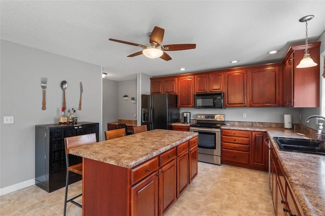 kitchen featuring a kitchen island, a breakfast bar, ceiling fan, a sink, and black appliances