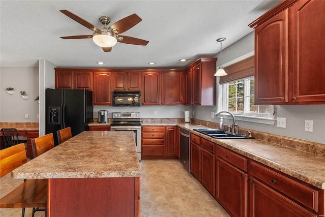 kitchen featuring a kitchen bar, hanging light fixtures, black appliances, a ceiling fan, and a sink