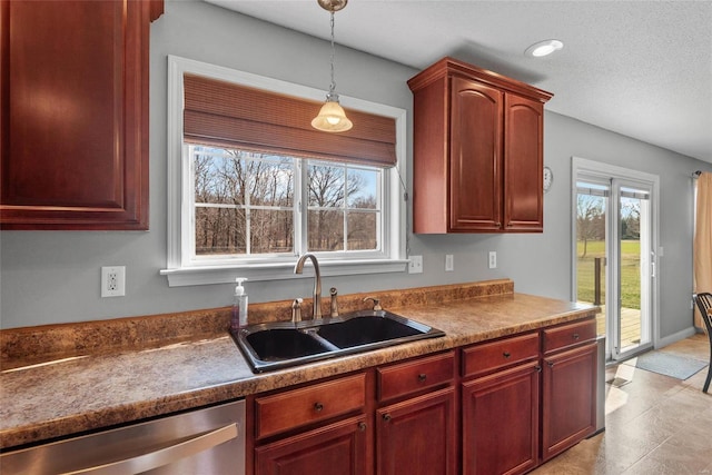 kitchen with a sink, decorative light fixtures, dishwasher, a textured ceiling, and reddish brown cabinets