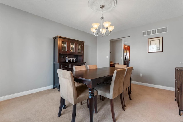 dining space featuring a notable chandelier, visible vents, light colored carpet, and baseboards