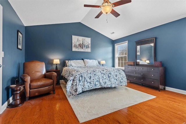 bedroom with a ceiling fan, vaulted ceiling, wood finished floors, and baseboards