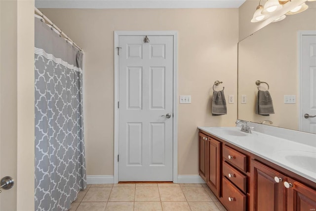 full bath featuring tile patterned flooring, double vanity, baseboards, and a sink