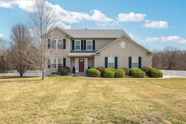 traditional home featuring a front yard, fence, and brick siding