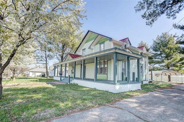 view of side of home featuring a carport, covered porch, metal roof, and a yard