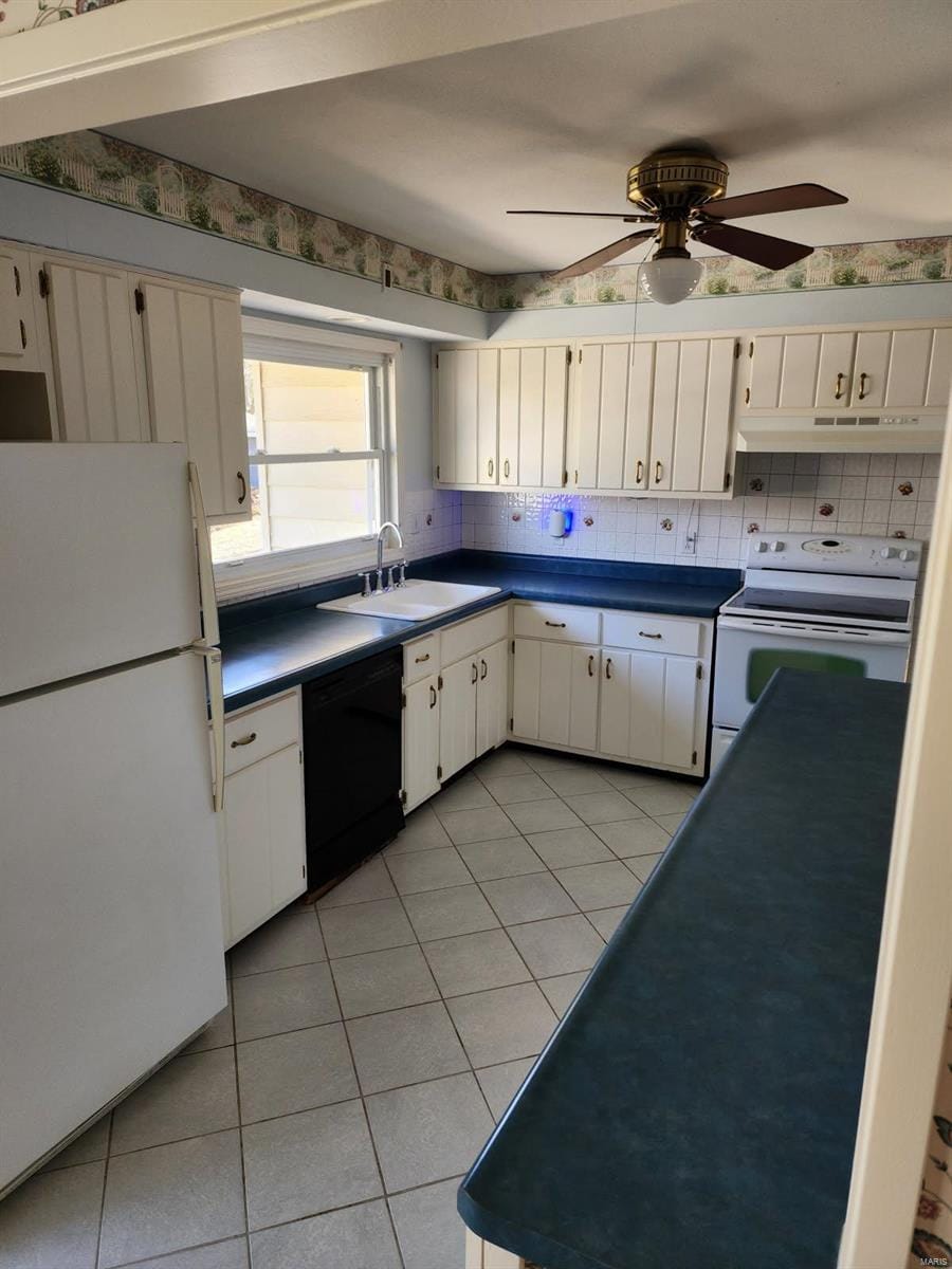 kitchen with dark countertops, white appliances, under cabinet range hood, and a sink