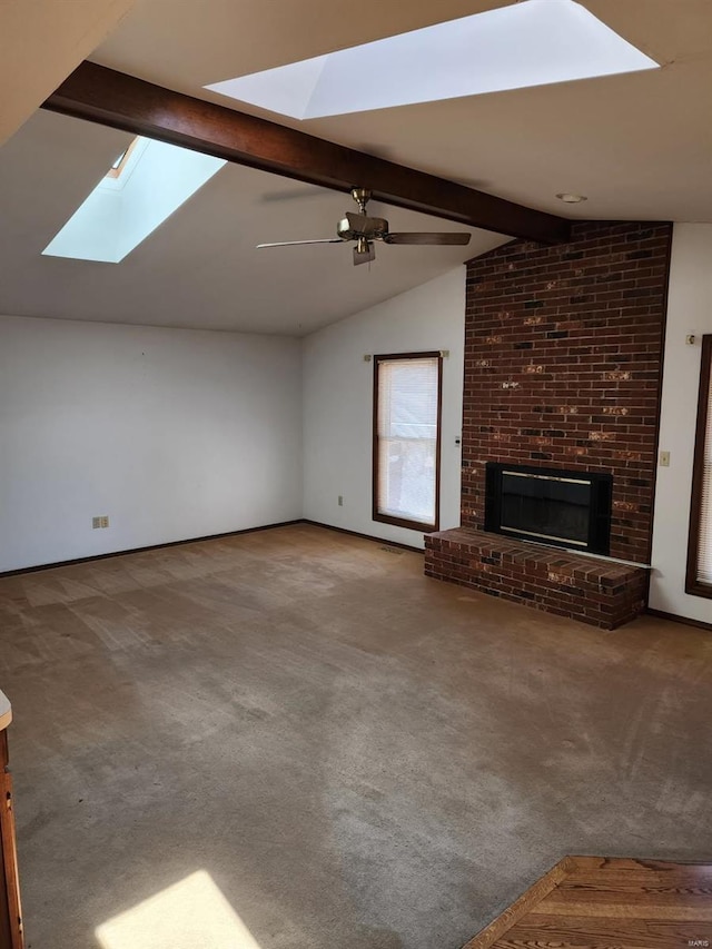 unfurnished living room featuring lofted ceiling with skylight, a brick fireplace, carpet, and ceiling fan