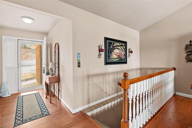 hall featuring an upstairs landing, wood finished floors, and baseboards