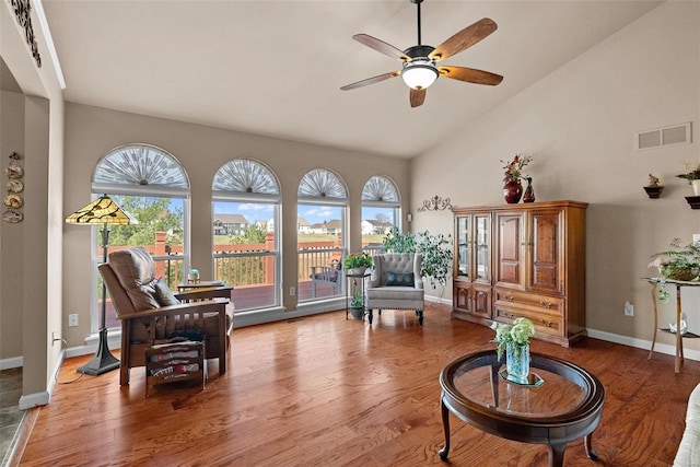 sitting room with wood finished floors, visible vents, baseboards, high vaulted ceiling, and ceiling fan