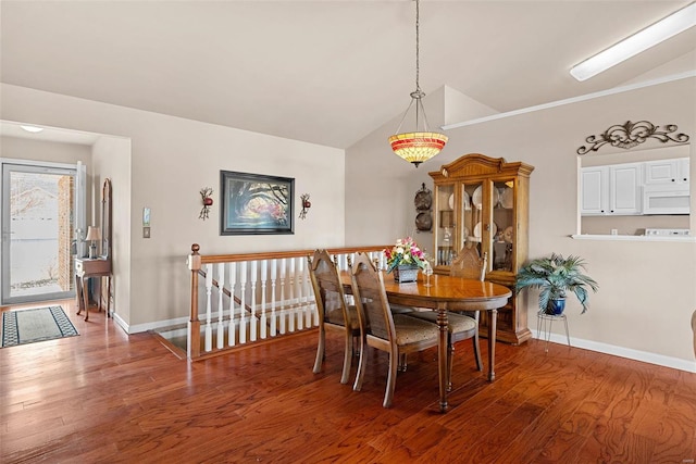 dining area featuring vaulted ceiling, baseboards, and wood finished floors