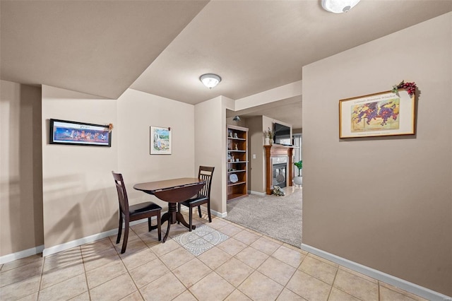 dining area with light tile patterned flooring, a glass covered fireplace, and baseboards