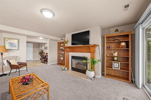 carpeted living area featuring baseboards, visible vents, and a high end fireplace