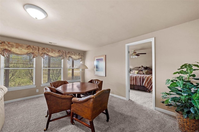 carpeted dining area featuring a ceiling fan and baseboards