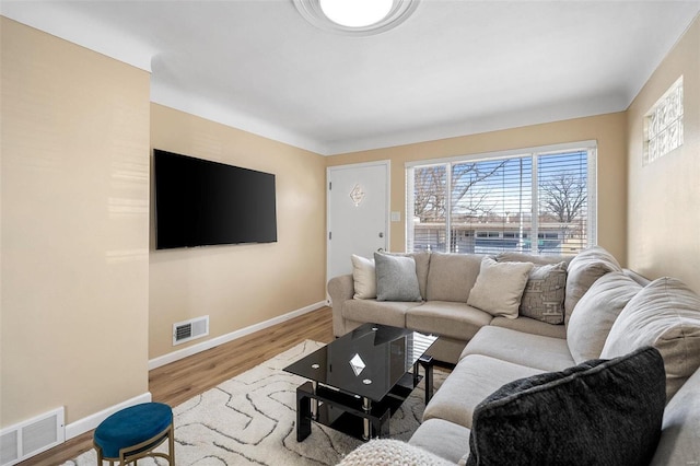 living room with visible vents, baseboards, and wood finished floors