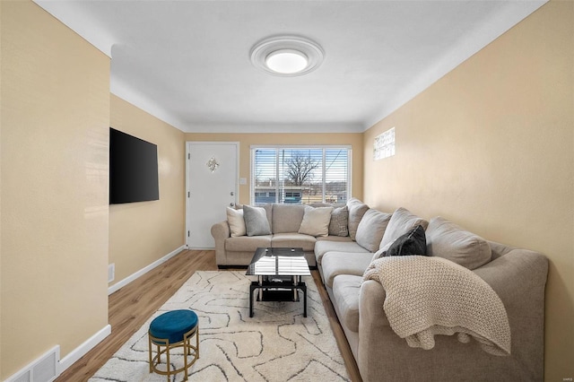 living room with baseboards, visible vents, and light wood-type flooring