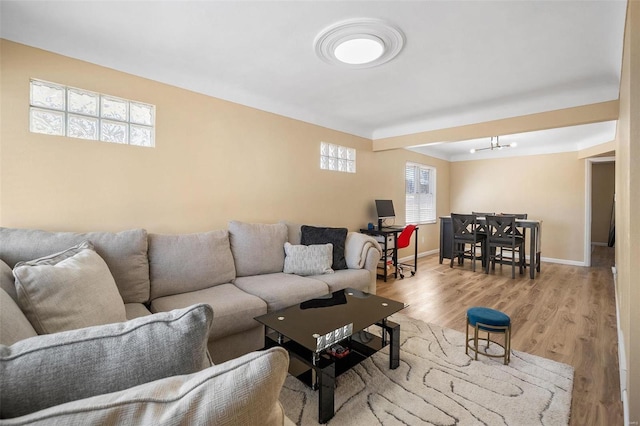 living area featuring an inviting chandelier, wood finished floors, and baseboards