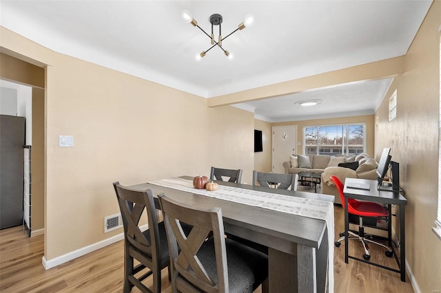 dining space with visible vents, a notable chandelier, light wood-style floors, and baseboards