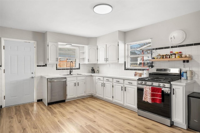 kitchen featuring open shelves, a sink, appliances with stainless steel finishes, white cabinetry, and a wealth of natural light