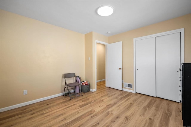 interior space with wood finished floors, visible vents, a closet, and baseboards