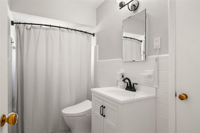 bathroom with vanity, tile walls, toilet, and a wainscoted wall