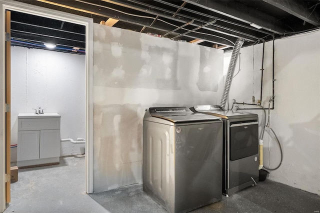 clothes washing area with a sink, laundry area, and washer and clothes dryer