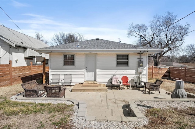 back of property with an outdoor living space, fence private yard, a patio, and roof with shingles