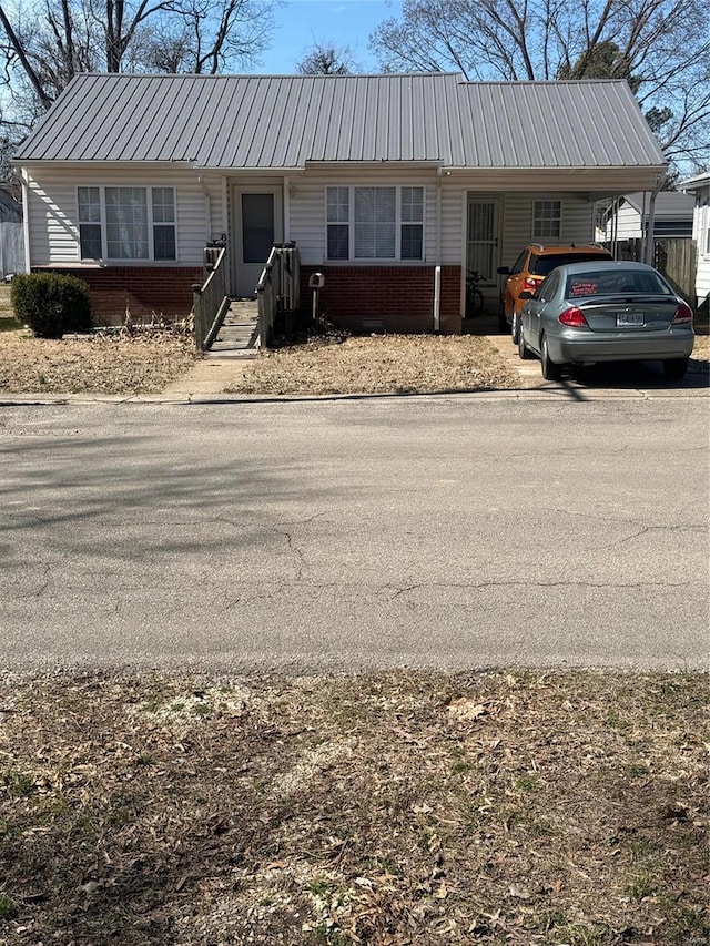 ranch-style house with brick siding, an attached carport, and metal roof