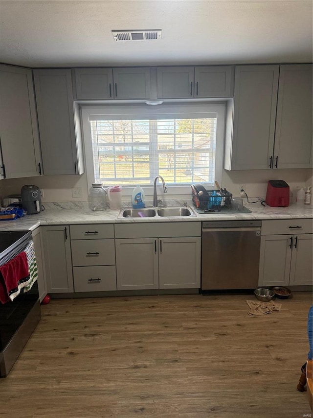 kitchen with visible vents, electric range, gray cabinets, a sink, and stainless steel dishwasher