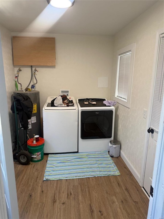 washroom featuring wood finished floors, water heater, separate washer and dryer, baseboards, and laundry area