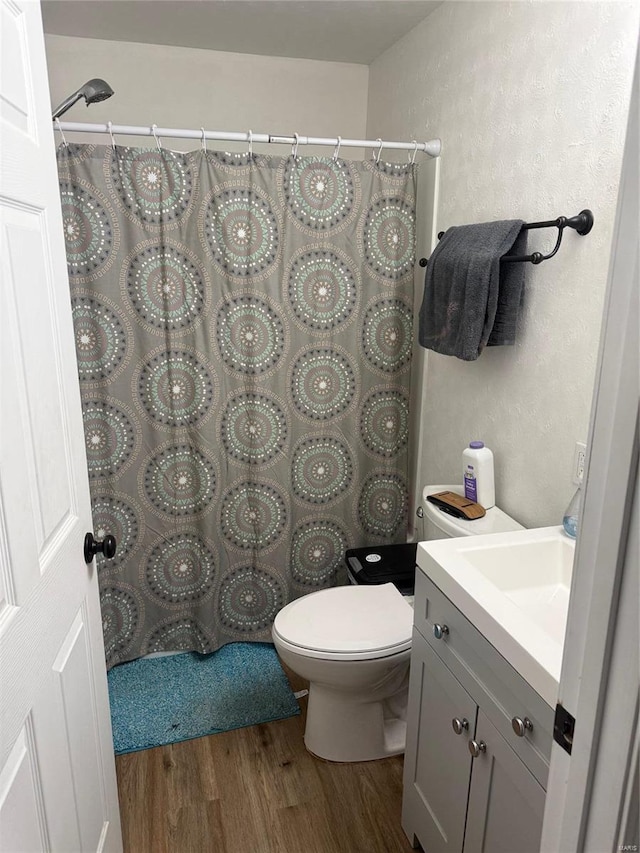 bathroom featuring curtained shower, toilet, vanity, and wood finished floors