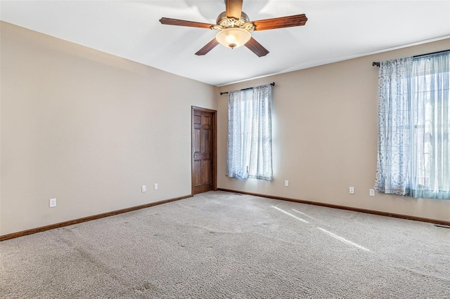 spare room featuring light carpet, plenty of natural light, ceiling fan, and baseboards