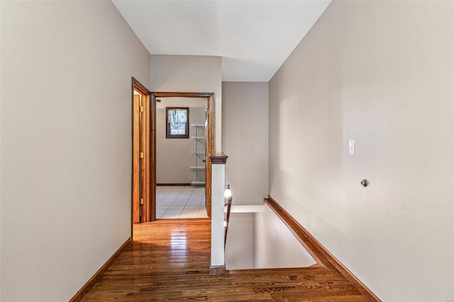 corridor with baseboards and wood finished floors