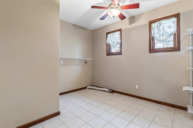 empty room with light tile patterned floors, a ceiling fan, and baseboards