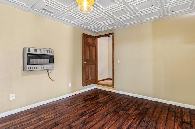 unfurnished room featuring heating unit, an ornate ceiling, dark wood-type flooring, and baseboards