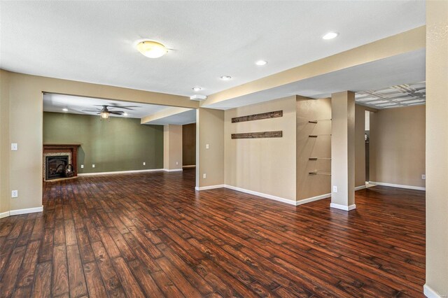 unfurnished living room featuring a ceiling fan, wood finished floors, recessed lighting, baseboards, and a brick fireplace