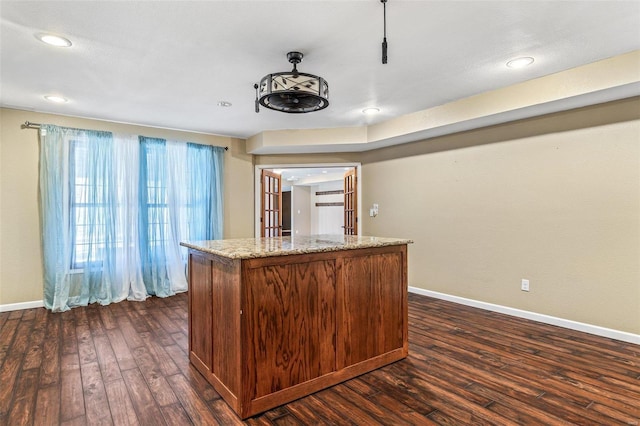 kitchen with a kitchen island, baseboards, light stone counters, recessed lighting, and dark wood-style flooring