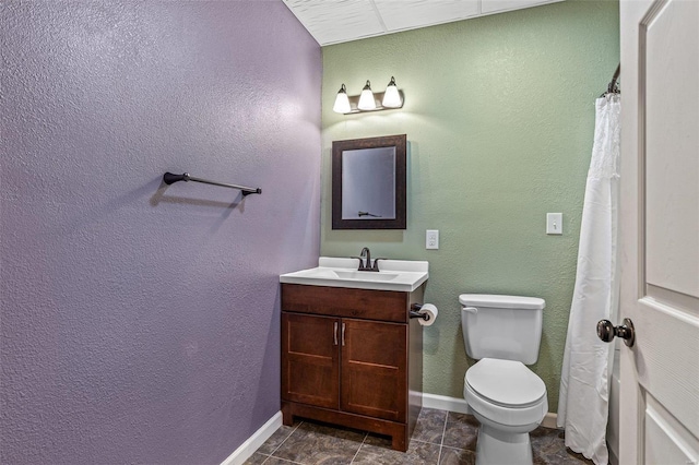 bathroom with vanity, toilet, a textured wall, and baseboards