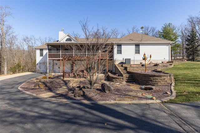 ranch-style house featuring a front yard, stairway, cooling unit, and a chimney