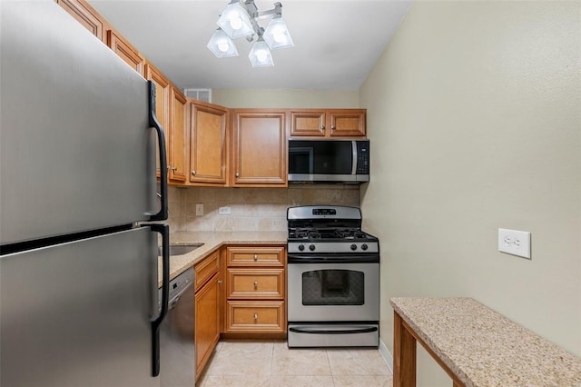kitchen with appliances with stainless steel finishes, backsplash, brown cabinets, and light tile patterned floors