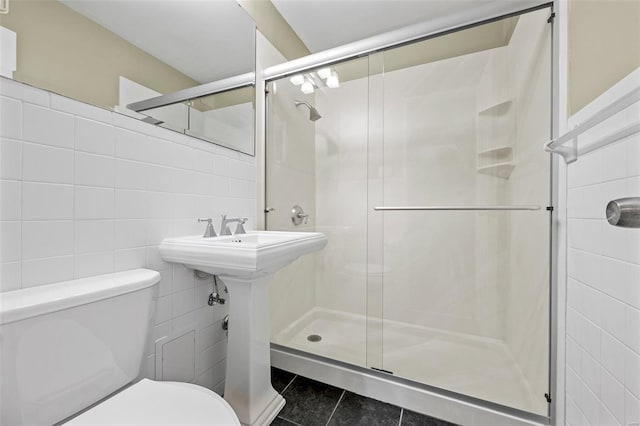 full bath featuring tile walls, tile patterned floors, a shower stall, and toilet