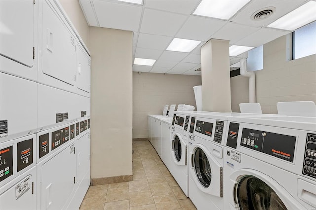 shared laundry area with visible vents, washing machine and dryer, stacked washer / dryer, and concrete block wall