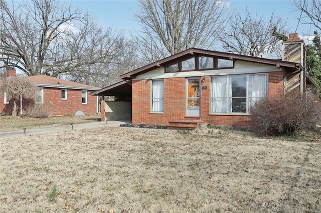 view of front of home with a carport, driveway, brick siding, and a chimney