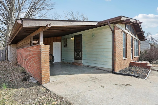 view of front of house with an attached carport, concrete driveway, and brick siding