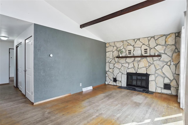 unfurnished living room featuring a fireplace, lofted ceiling with beams, wood finished floors, and baseboards