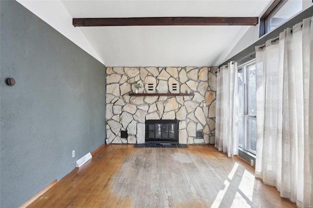 unfurnished living room with visible vents, a fireplace, vaulted ceiling with beams, and wood finished floors